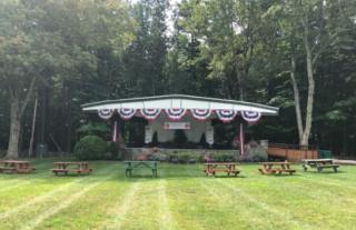 Town band stand decorated with patriotic buntings, town forest in the background
